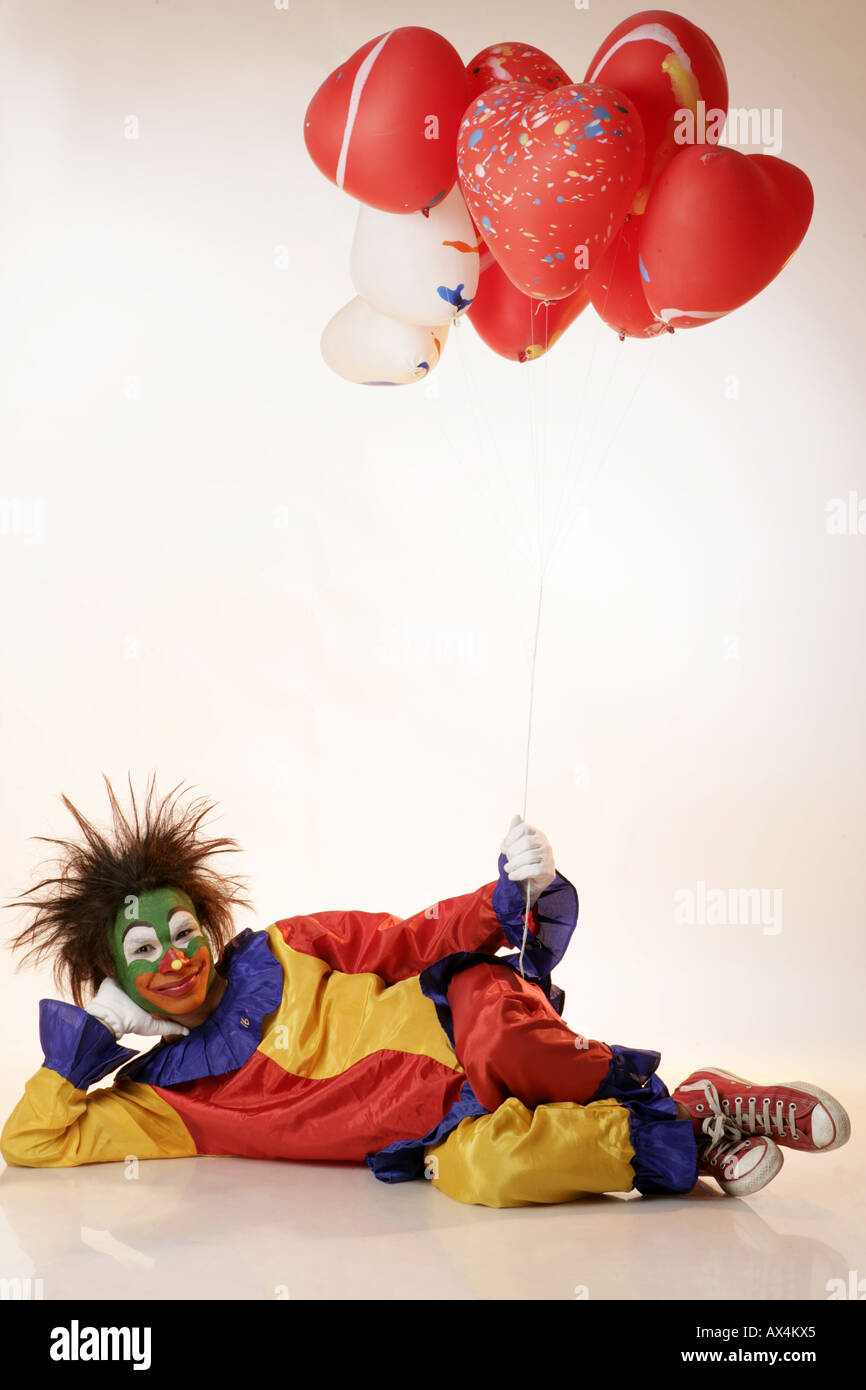 Ritratto di un joker sdraiato sul pavimento e palloncini di contenimento Foto Stock