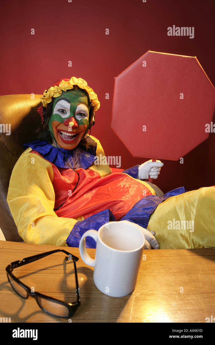 Ritratto di un joker seduti su una sedia e che mostra la bacheca Foto Stock