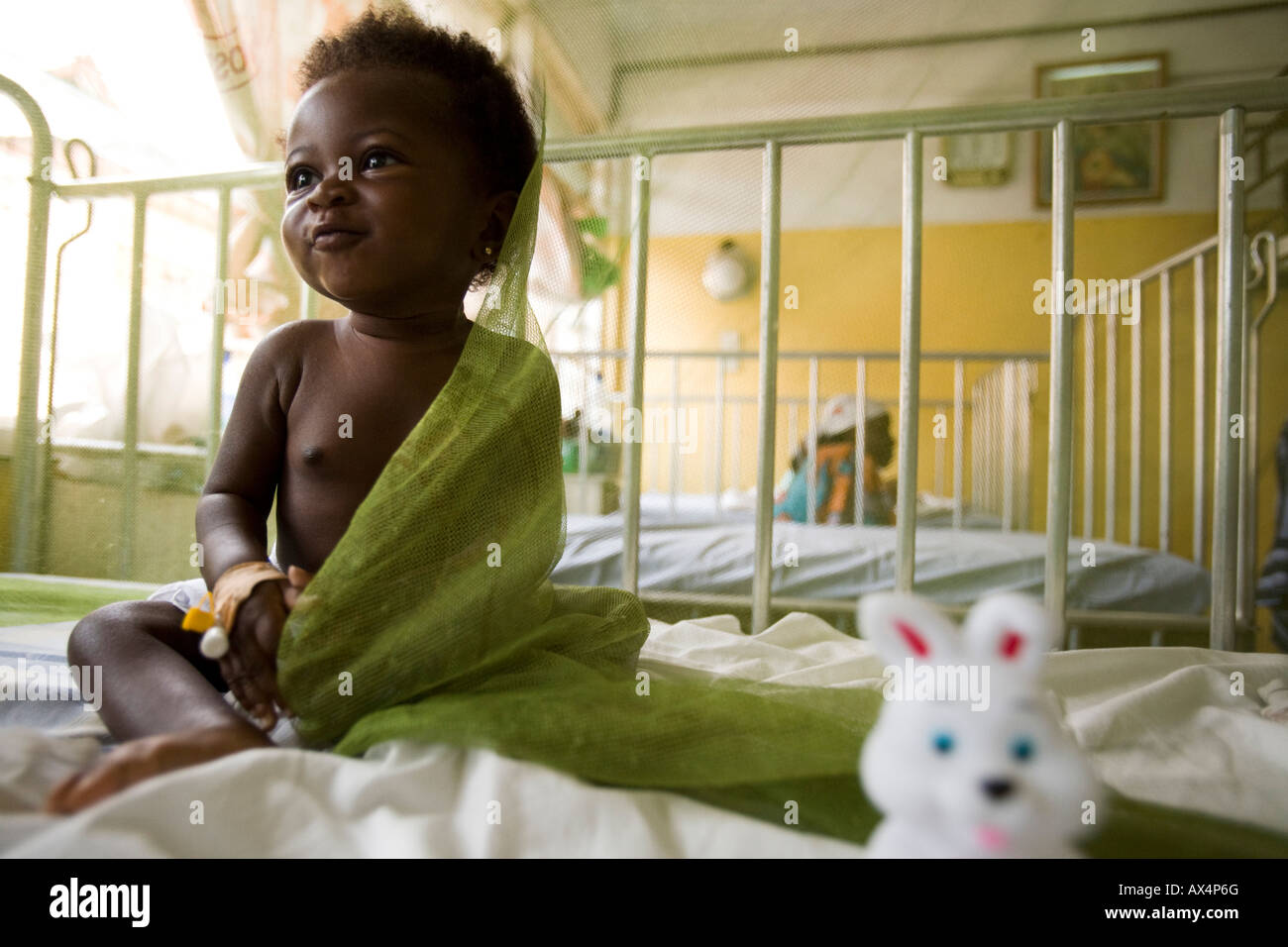 Una bambina si siede sotto una zanzariera Foto Stock