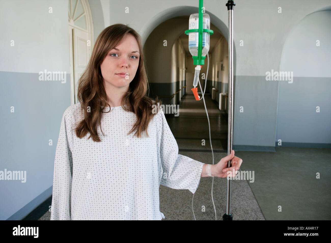 Una donna in piedi con una flebo IV in un corridoio di ospedale Foto Stock
