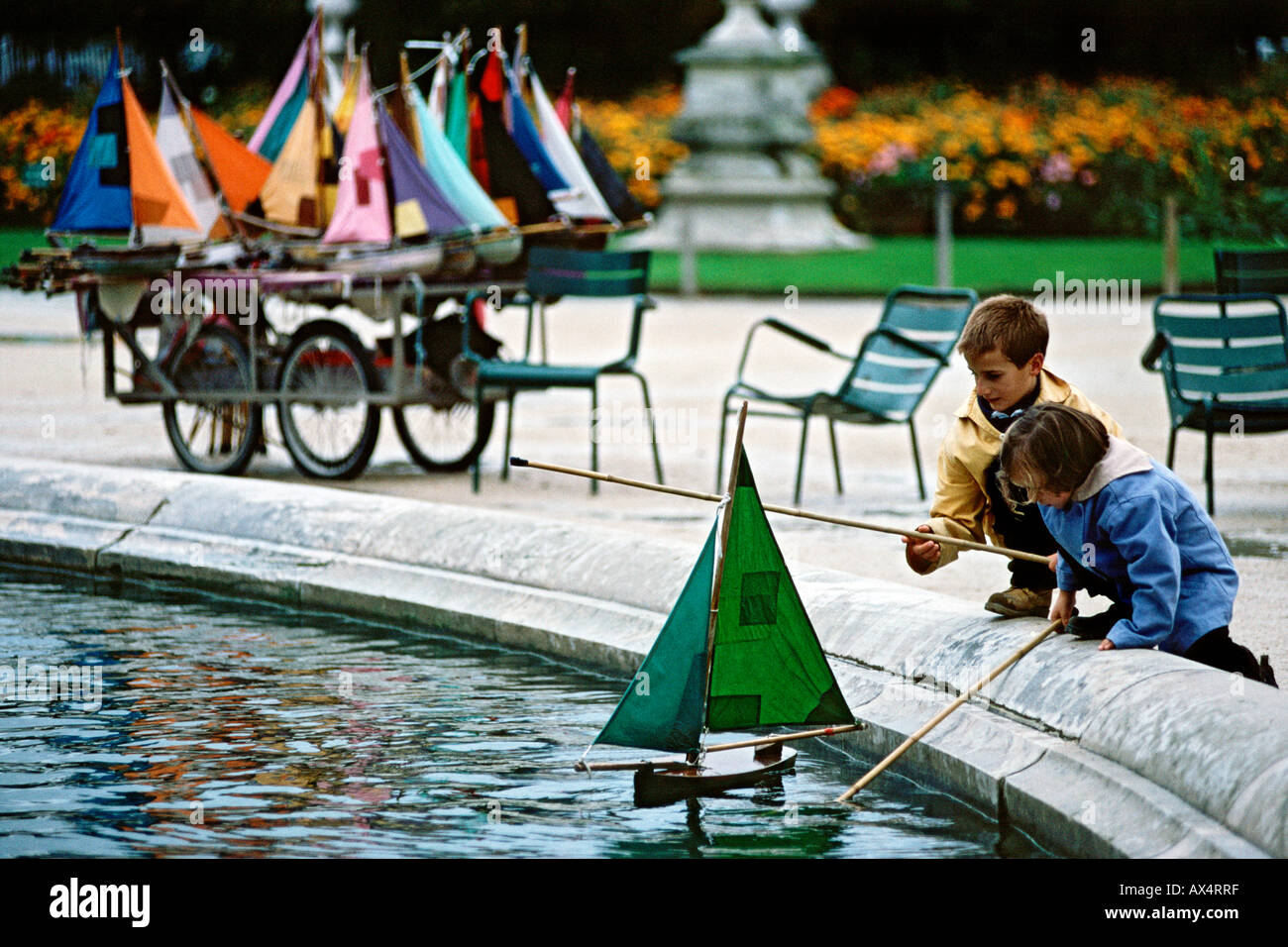 Bambini che giocano con il modello di imbarcazioni a vela sullo stagno nei Jardins des Tuileries a Parigi. Foto Stock