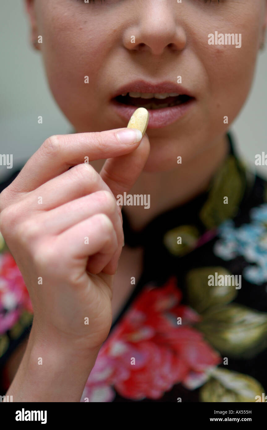 Una giovane donna assumendo integratori alimentari Foto Stock