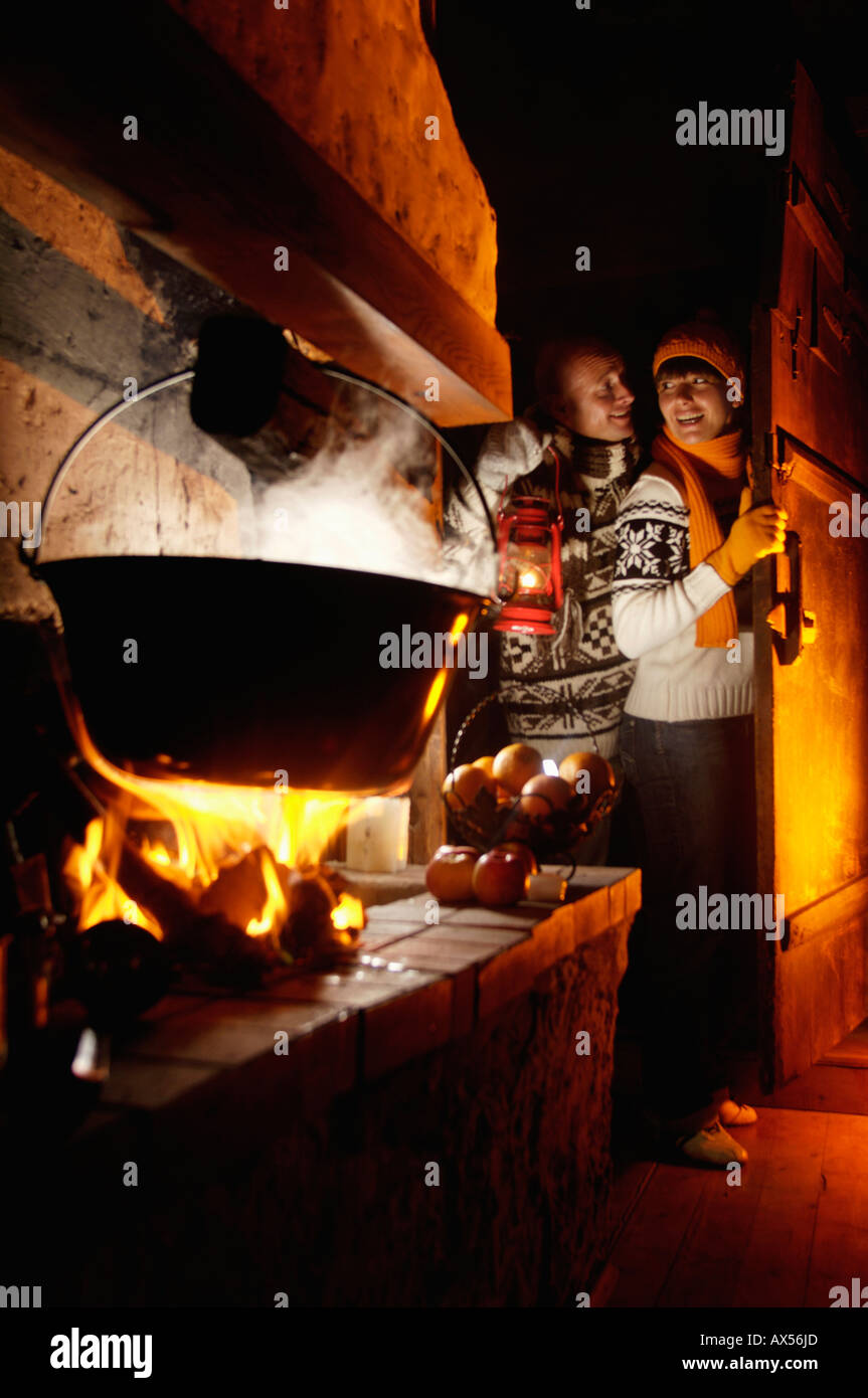 Matura in rifugio alpino vicino al camino, uomo con lampada Foto Stock