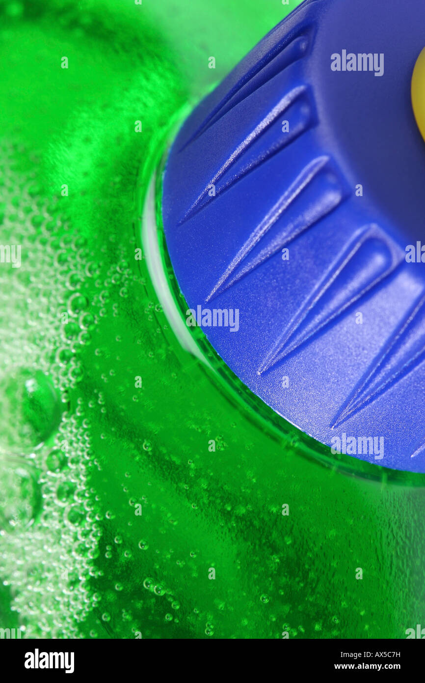 Detersivo liquido con coperchio blu, getto giallo e verde liquido di pulizia con bolle di aria Foto Stock