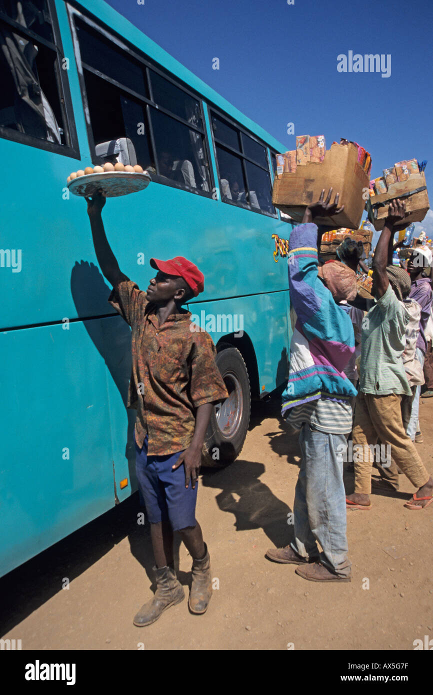Giovani uomini che lavorano come ambulanti tentare di vendere i rinfreschi per passeggeri di un autobus, Moshi, Tanzania. Foto Stock
