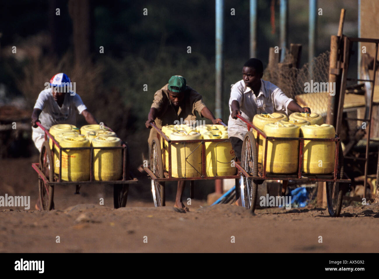 I ragazzi di spingere carrelli con acqua potabile contenitori per la vendita, Himo, Tanzania. Foto Stock
