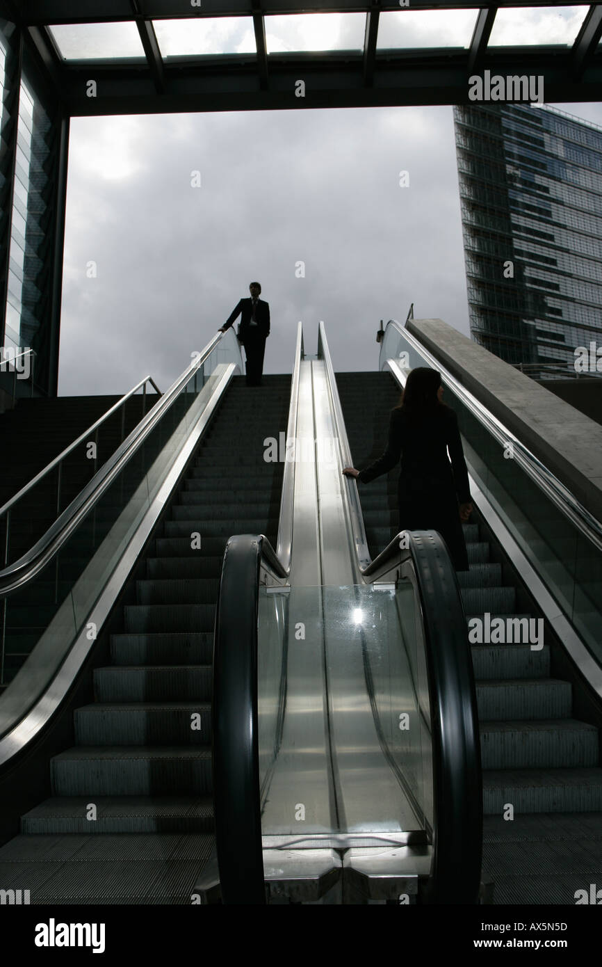 Un imprenditore e imprenditrice cavalcare un Escalator Foto Stock