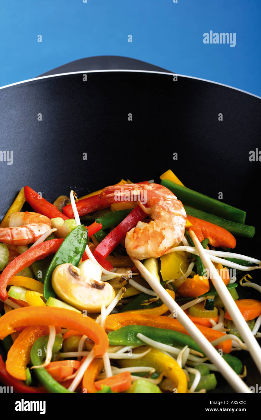 Verdure e gamberi cotti nel wok con bastoni di trinciatura Foto Stock