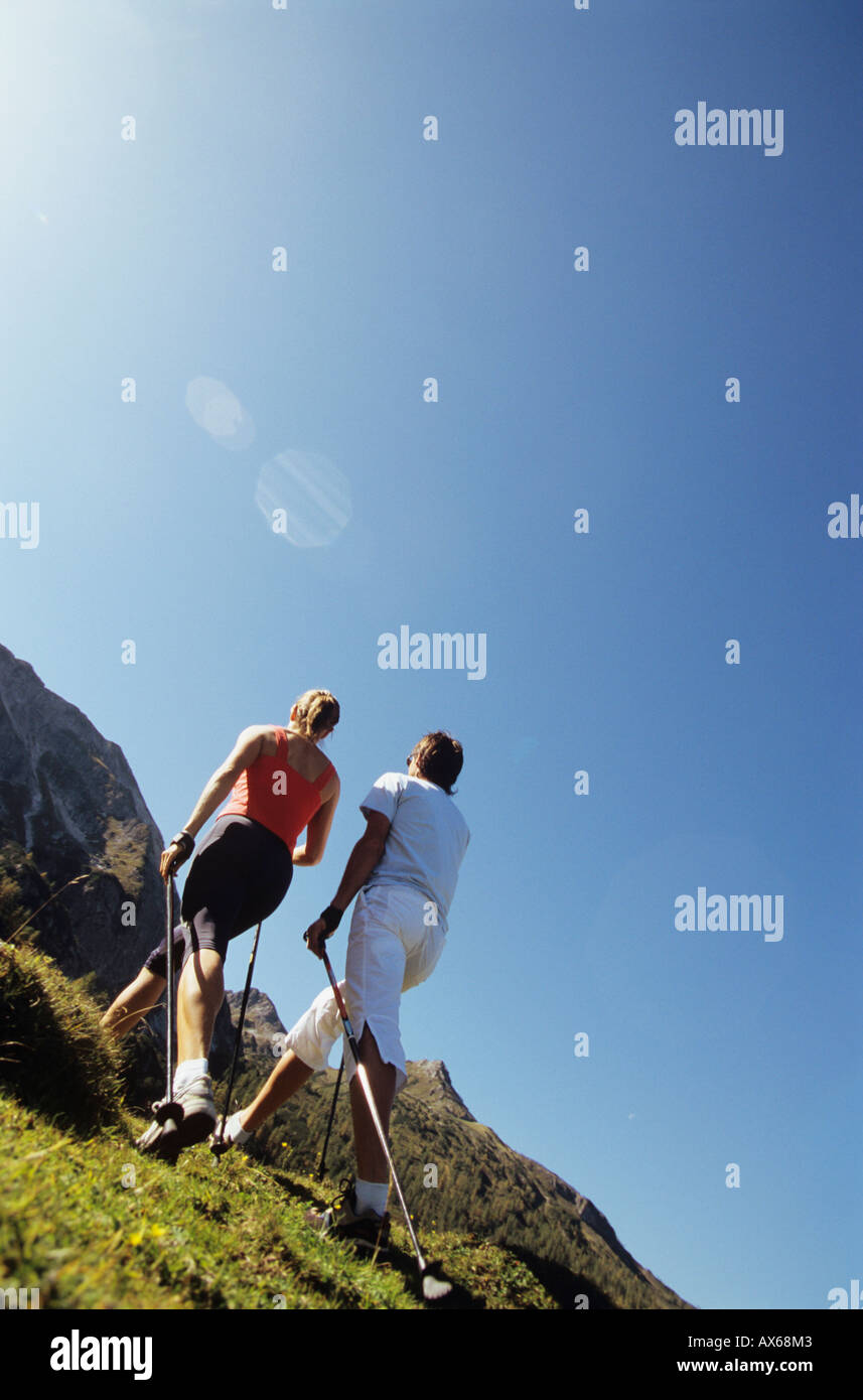 Paio di praticare il nordic walking in montagna, vista posteriore Foto Stock