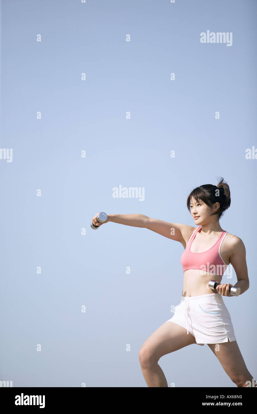 Una giovane donna lavora con l aiuto dei pesi Foto Stock