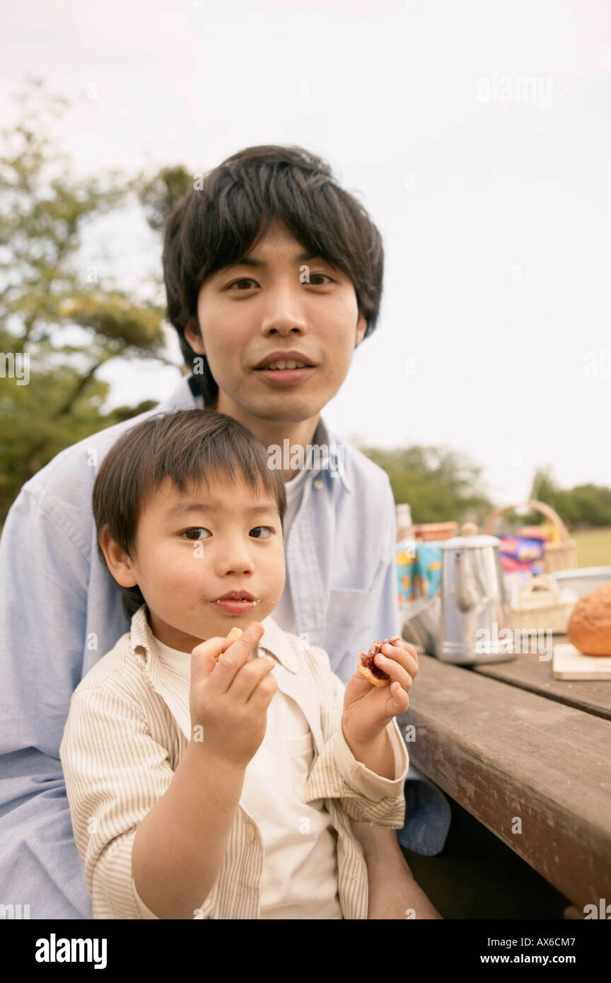 Un piccolo ragazzo seduto sul suo giro dei padri come si mangia su Foto Stock