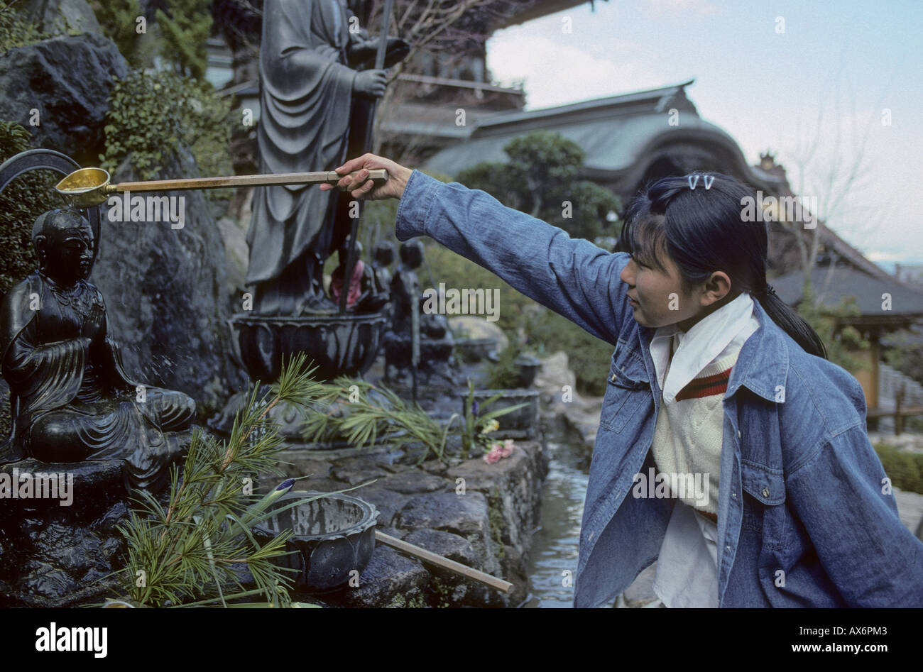 School girl rendendo offrendo il tempio Daishoin l'isola di Miyajima in Giappone Foto Stock