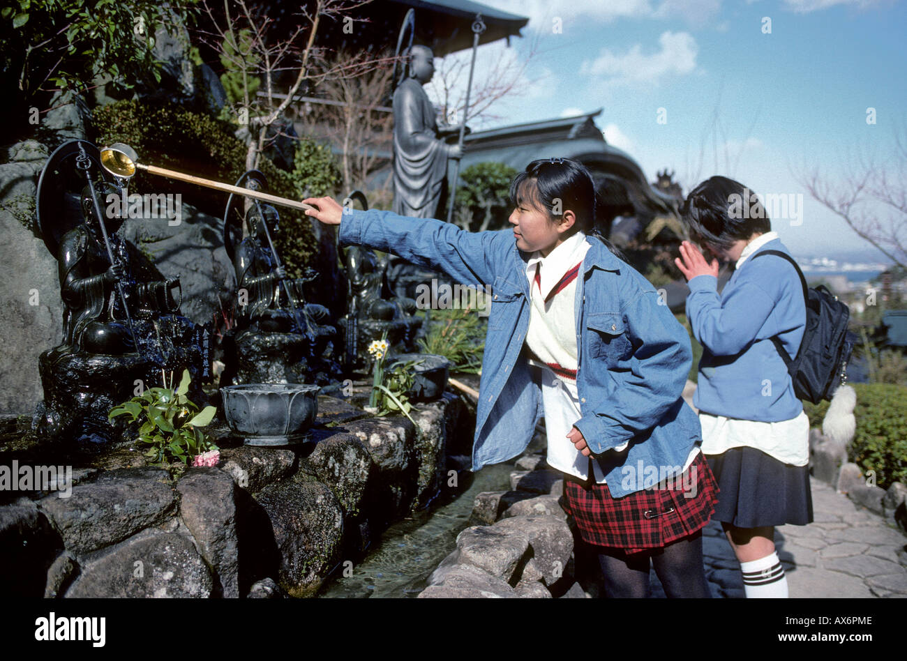 Le ragazze della scuola facendo offerte Tempio Daishoin l'isola di Miyajima in Giappone Foto Stock