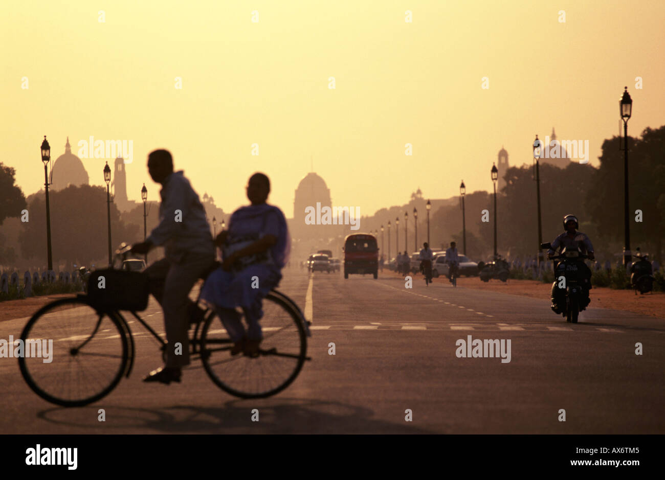 Un giovane su un pedale di bicicletta passato la capitale Building a New Delhi in India al tramonto Foto Stock