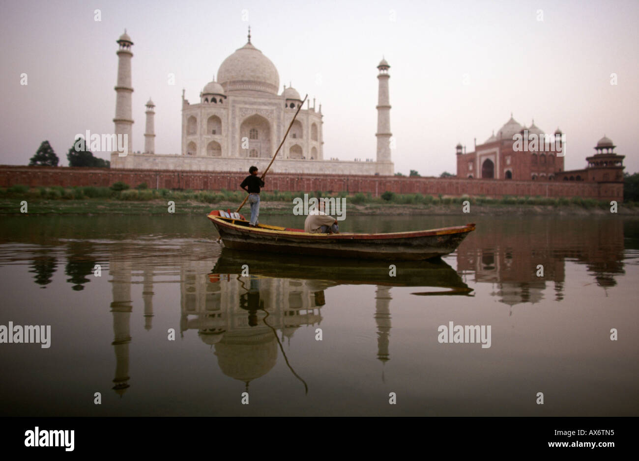 Un uomo che attraversa un fiume in barca dietro il Taj Mahal Foto Stock