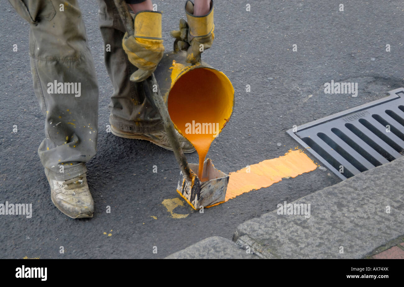 Pittura a mano singola linea gialla dalla fogna grattugiare sulla strada con bollitore di acqua calda di vernice e utensile di marcatura, Cheam, Londra, Inghilterra Foto Stock