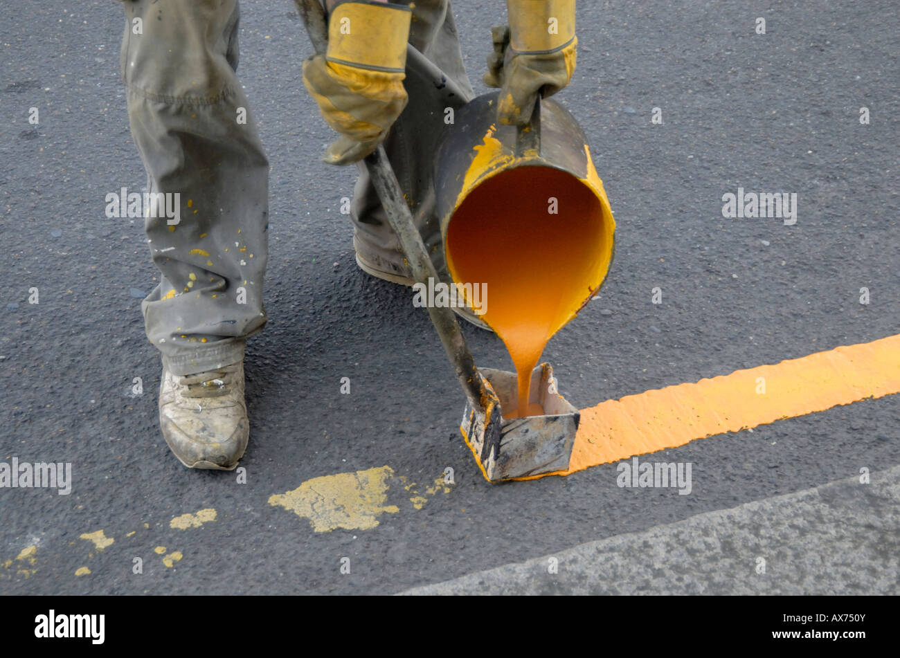 Pittura a mano singola linea gialla sulla strada con bollitore di acqua calda di vernice e utensile di marcatura, Cheam, a sud di Londra - Inghilterra Foto Stock