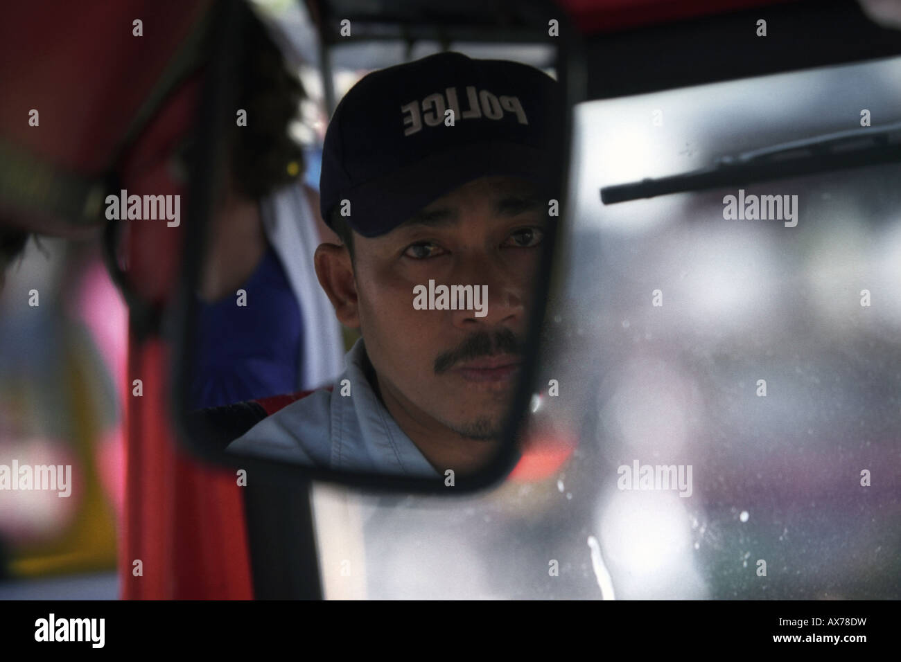Un Tuk Tuk driver, alla guida della sua Tuk Tuk nel centro cittadino di Bangkok. Fotografato mentre sul retro di Tuk Tuk guardando lo specchio dei driver. Foto Stock