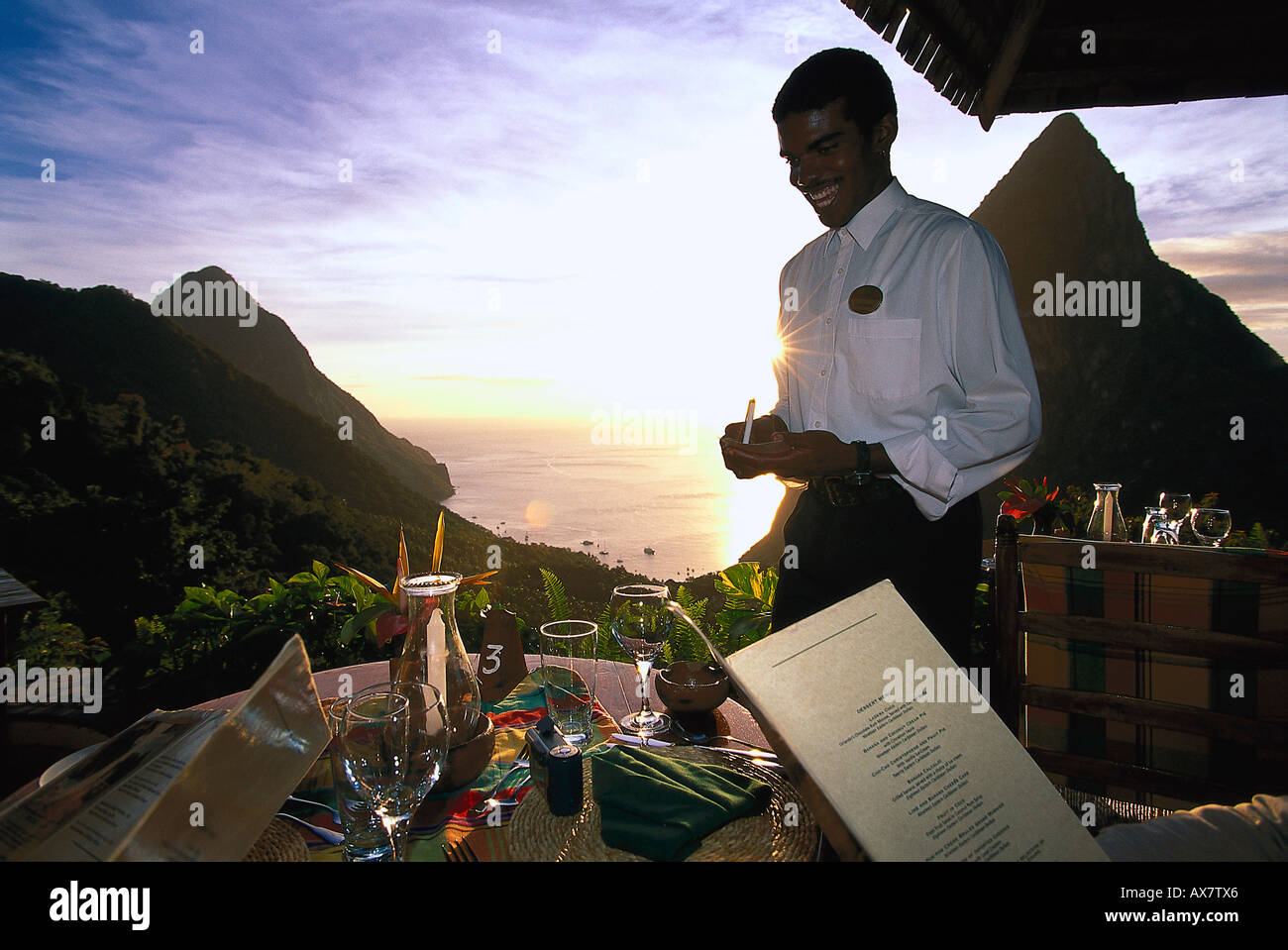 Ridendo cameriere permanente sulla terrazza del ristorante Dasheene, Ladera Resort Soufriere, St. Lucia, Caraibi Foto Stock