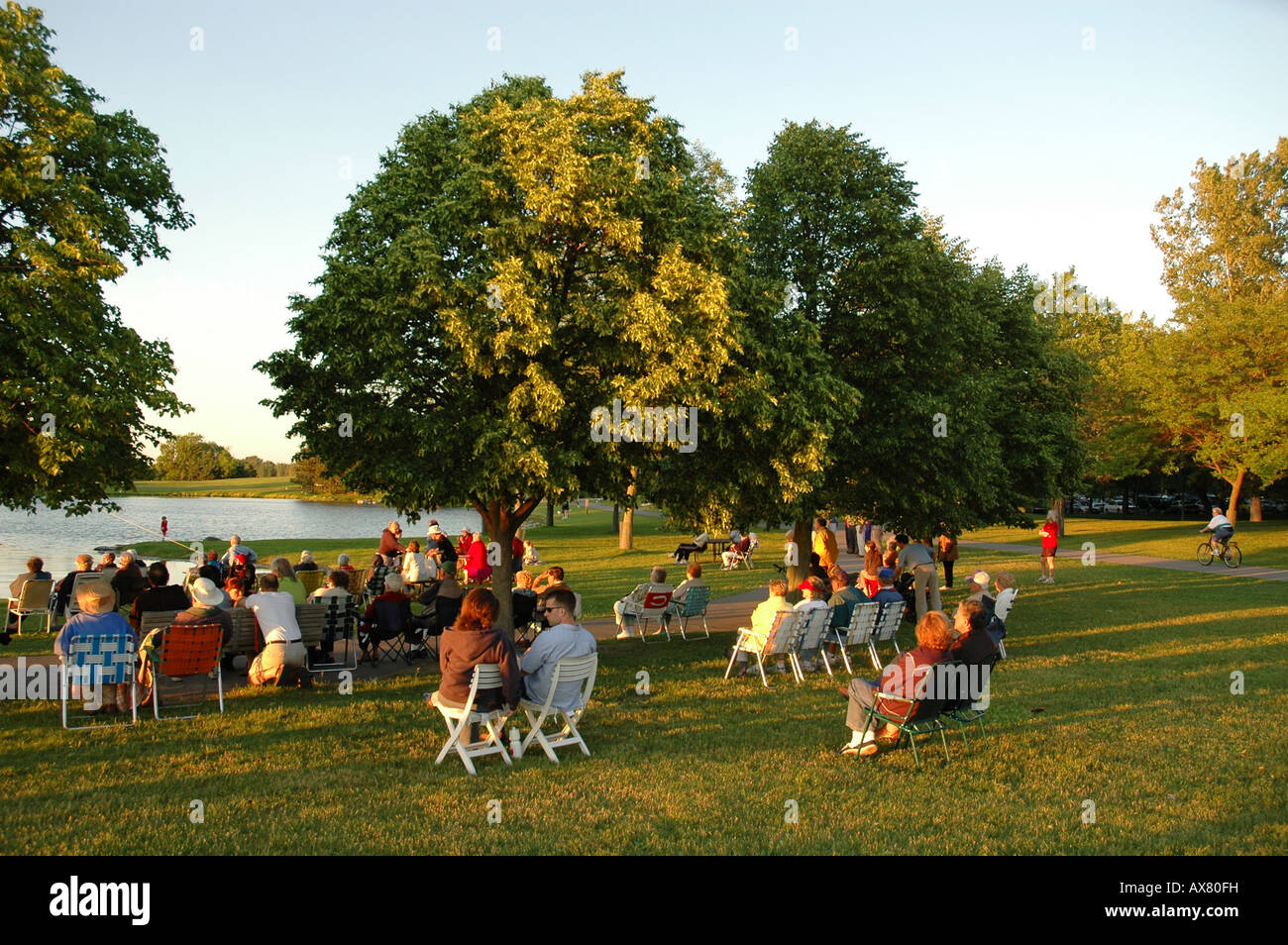 Un gruppo di persone si riuniscono in un parco di sera per guardare eventi della comunità Foto Stock