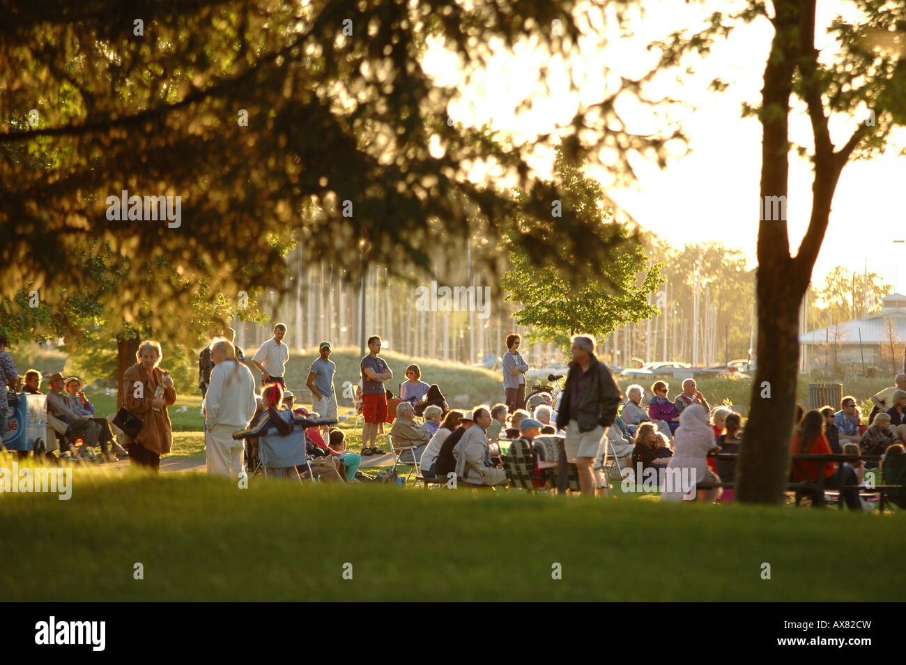 Un grande gruppo di persone si riuniscono in un parco di sera per guardare eventi della comunità Foto Stock
