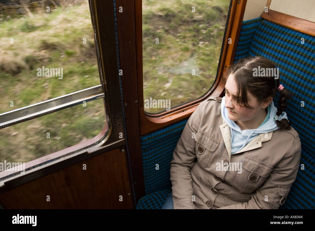 Ragazza adolescente a guardare fuori di un vagone ferroviario. Il treno è operativo su Worth Valley Railway nel West Yorkshire, Inghilterra, Regno Unito. Foto Stock