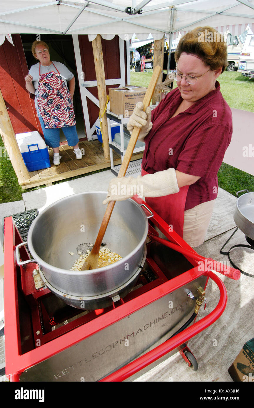 Piccola donna eseguire attività di vendita di bollitore popcorn Foto Stock