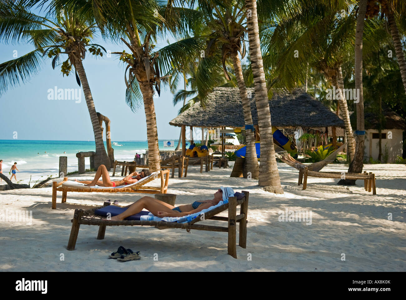 Donne e rilassante di sole sotto le palme a La Villa Beach Resort, sulla costa orientale di Zanzibar, Tanzania Foto Stock