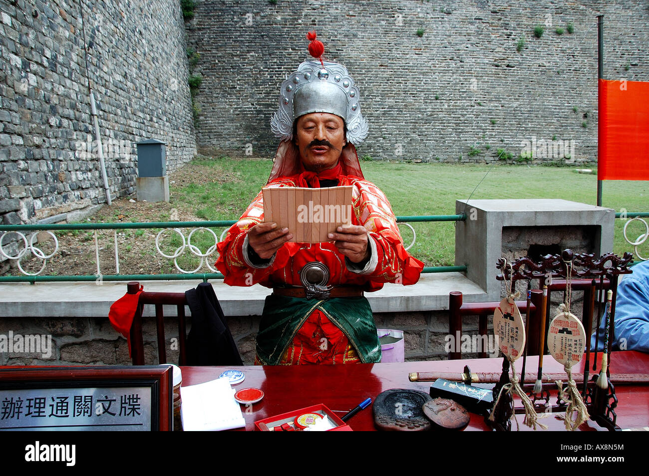 Un uomo vestito da una guardia della Dinastia Ming (1368 a 1644 AD) rilascio passa ai turisti di fronte al Shan Hai Guan, Cina. Foto Stock