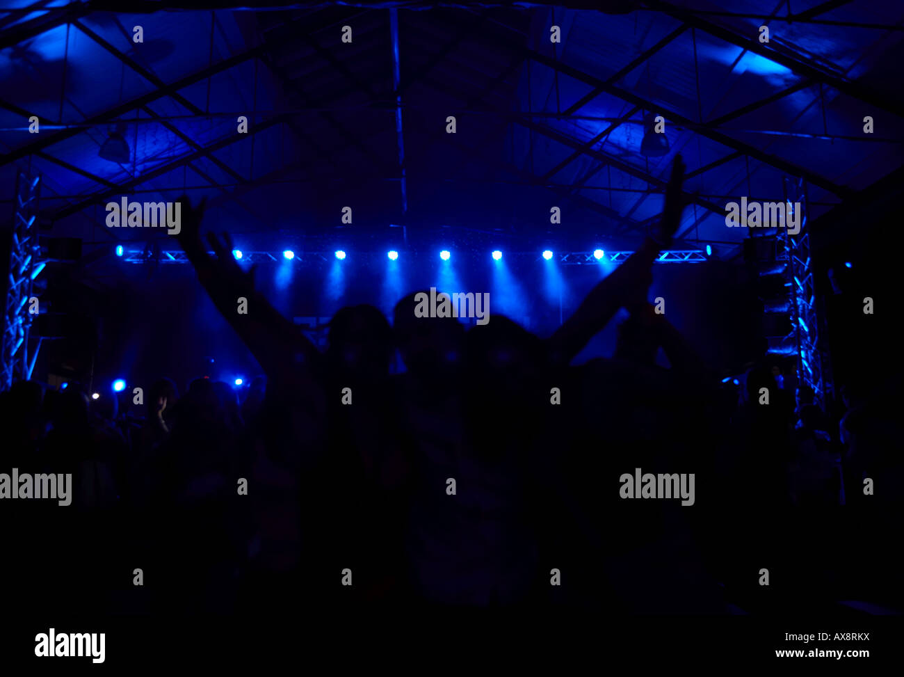Frequentatori di concerto con le braccia in aria nella parte anteriore della fase di illuminazione in corrispondenza di un evento di ballo a Belfast Irlanda del Nord Foto Stock