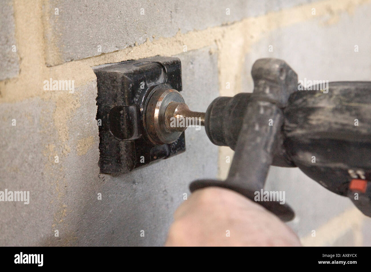 Un edificio la perforazione di 3 pollici (76mm) foro quadrato in una parete utilizzando un attacco SDS per consentire il montaggio di metallo Scatole da parete per connettori femmina Foto Stock