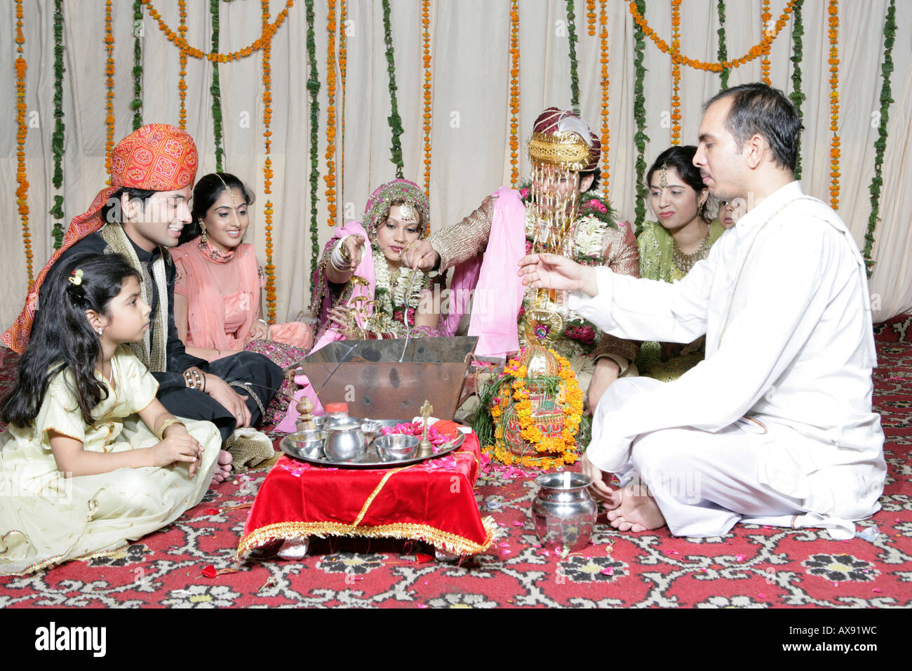 Sposa sposo sposarsi con la loro relativa e un sacerdote seduti intorno a loro Foto Stock
