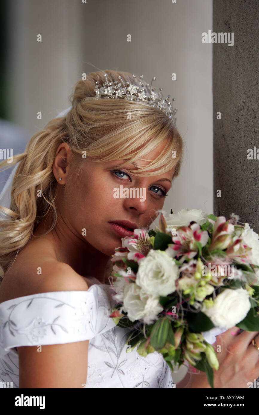 Ritratto di piuttosto giovane sposa in bianco tradizionale abito da sposa azienda bouquet di fiori. Foto Stock