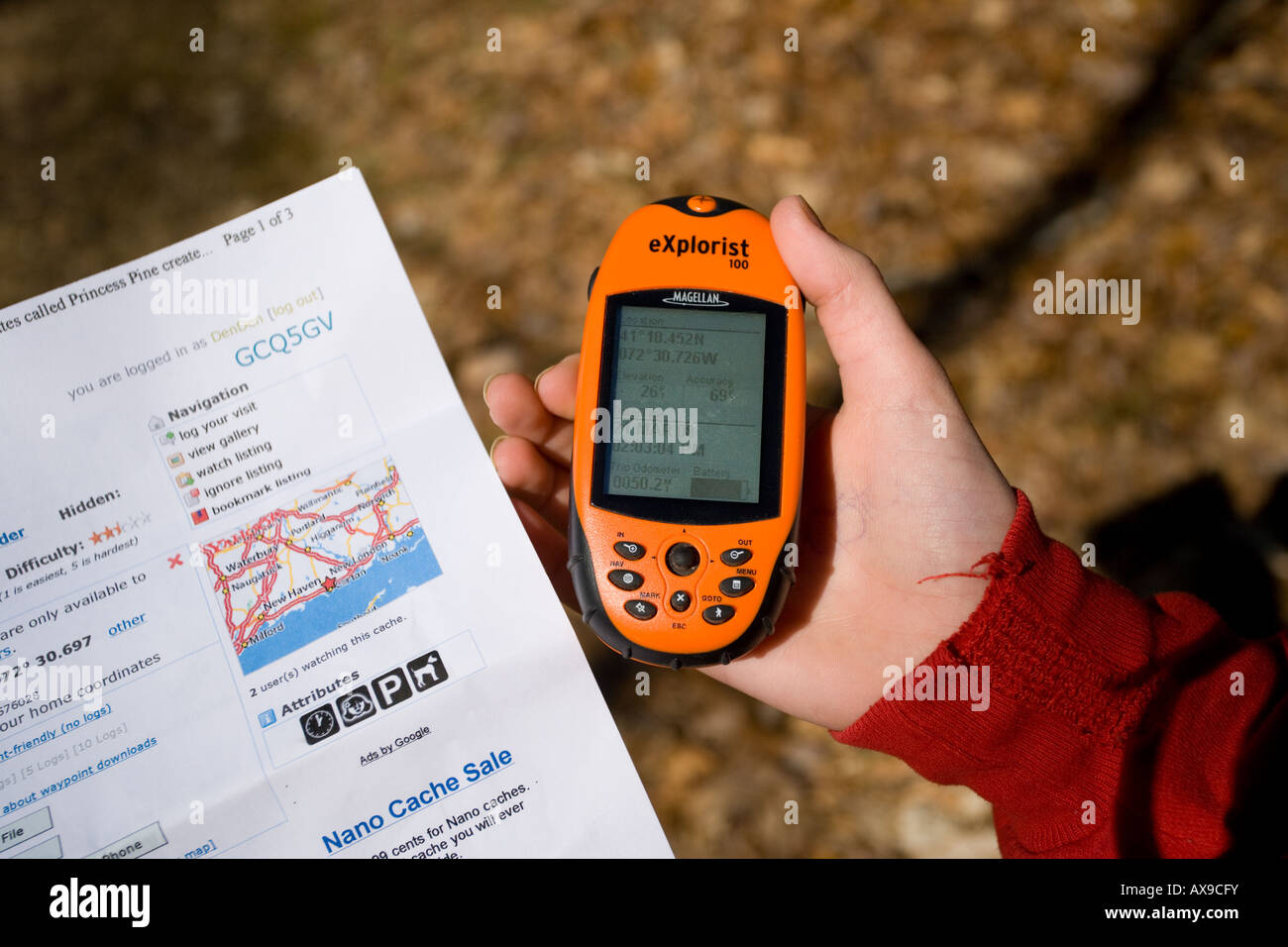 Una famiglia utilizza un hand-held unità GPS per trovare un geocache o Geo cache che è un escursionismo attività dove la gente cerca di scatole Foto Stock