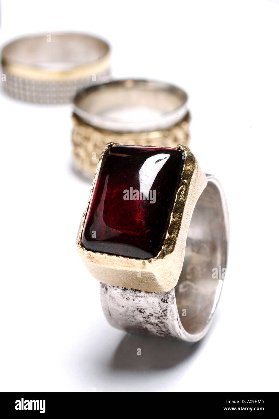 Ruby su un anello in argento su sfondo bianco con gli anelli di nozze in background Foto Stock