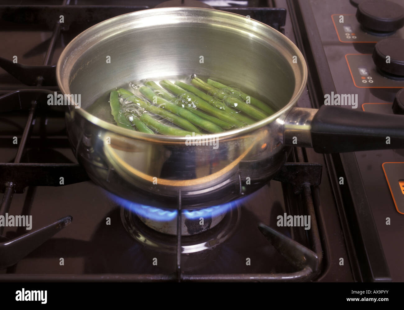 Pentola di fagioli verdi ebollizione su fornelli a gas impugnatura isolante Foto Stock