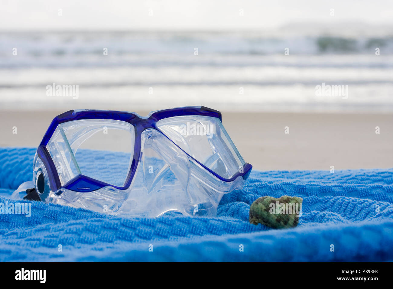 Maschera subacquea e shell su un asciugamano blu sulla spiaggia Foto Stock