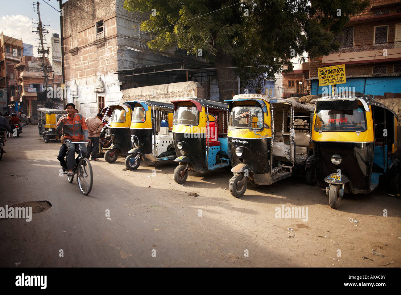 Due giovani ragazzi in sella ad una bicicletta singolo passato una fila di auto-rickshaws in Jodhpur, Rajasthan, India. Foto Stock