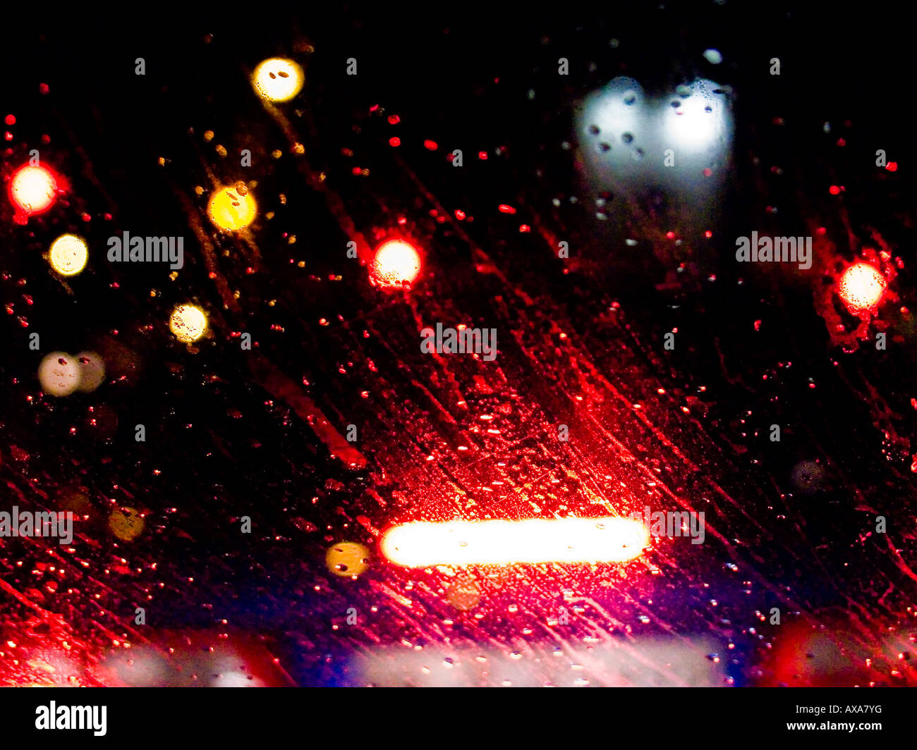 Luci auto visto attraverso un vetro bagnato dalla pioggia durante la notte Foto Stock