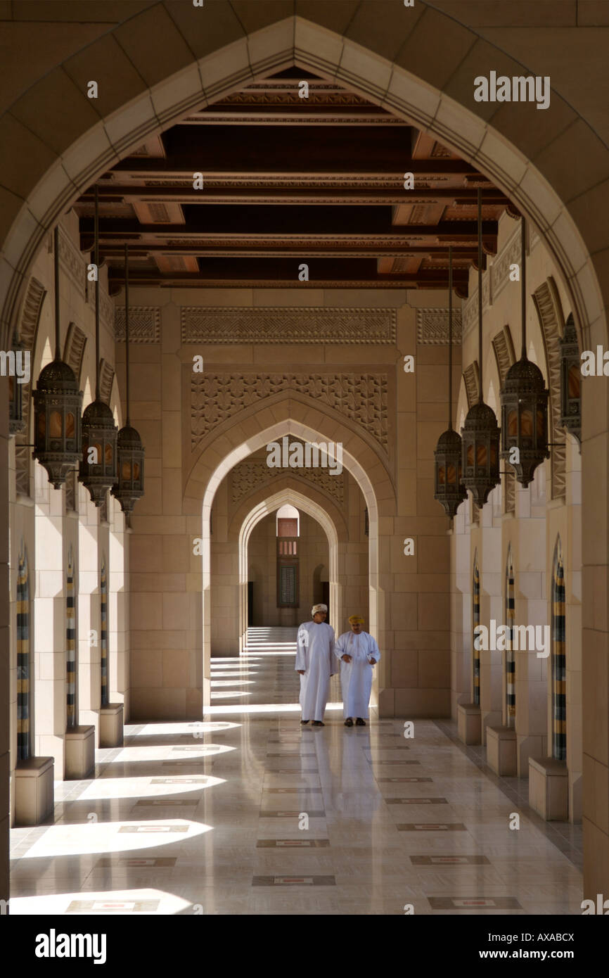 Due uomini Omani camminando tra le arcate che circonda il Sultan Qaboos grande moschea di Muscat, della capitale di Oman. Foto Stock