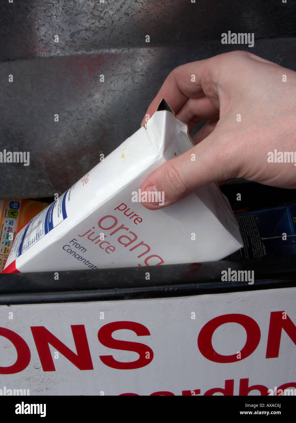 Man mano collocando un vuoto riciclabili puliti succo di frutta il contenitore in un contenitore di riciclaggio al deposito di riciclaggio Foto Stock