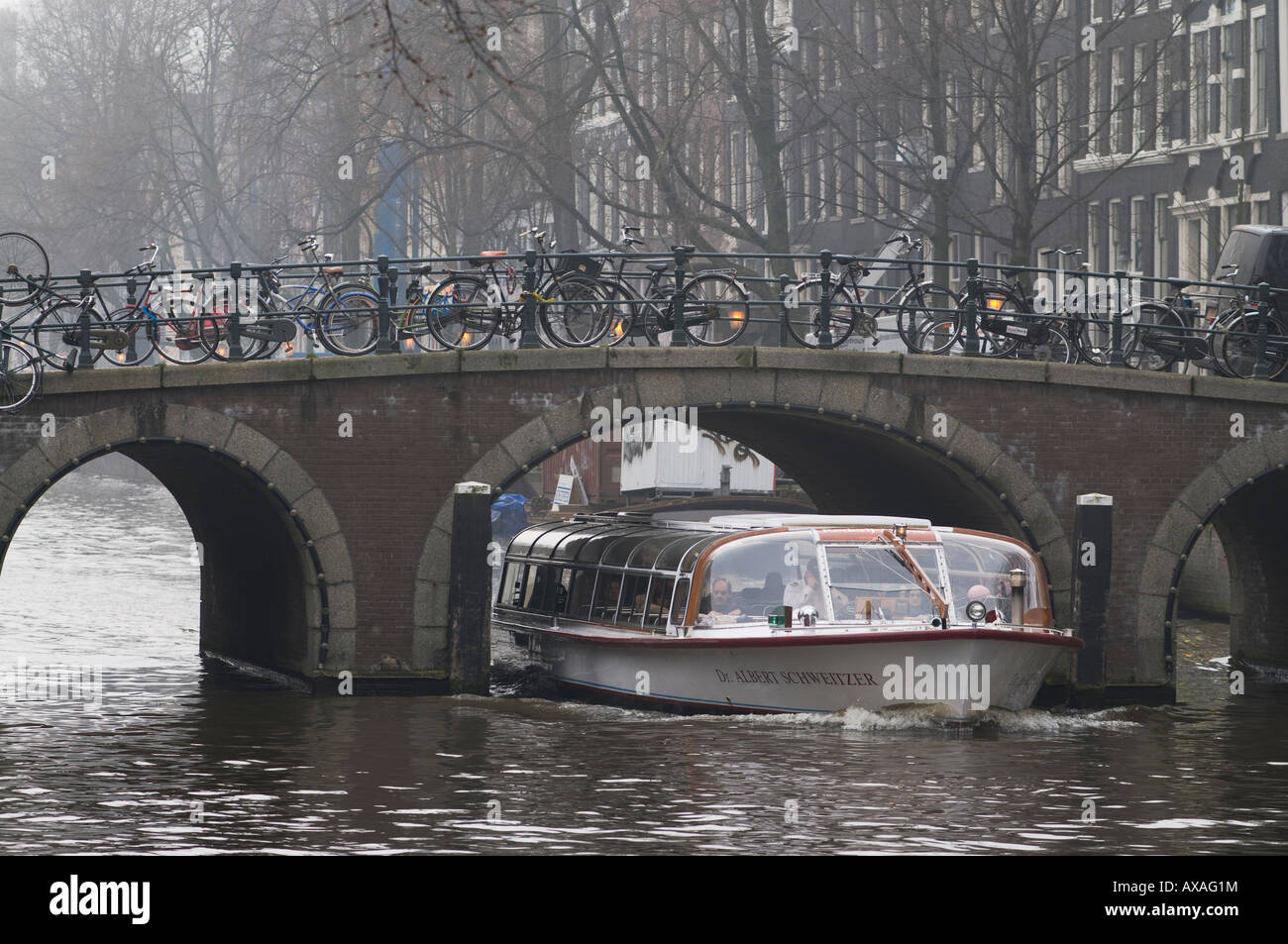 Un canal boat andare sotto un ponte in Amsterdam Foto Stock