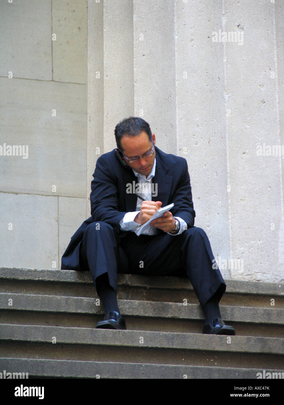Business man parlando sul suo telefono cellulare e creare note vicino al New York Stock Exchange a Wall Street, USA, Manhattan, New Y Foto Stock