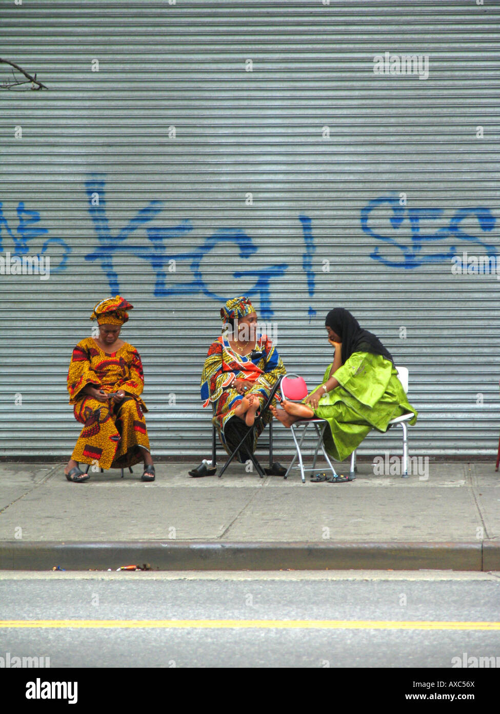 Tre donne seduto davanti di serrande di un negozio chiuso a 125th Street in Harlem, STATI UNITI D'AMERICA, Manhattan Harlem, New York Foto Stock