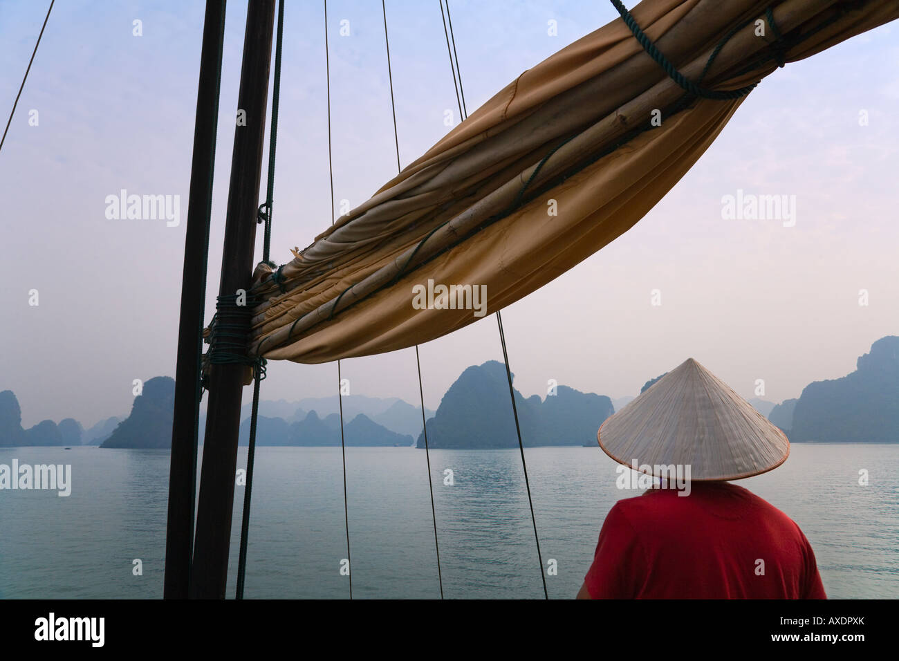 Ragazza con cappello conico su una barca di posta indesiderata e del carso isole nella baia di Halong Vietnam Foto Stock