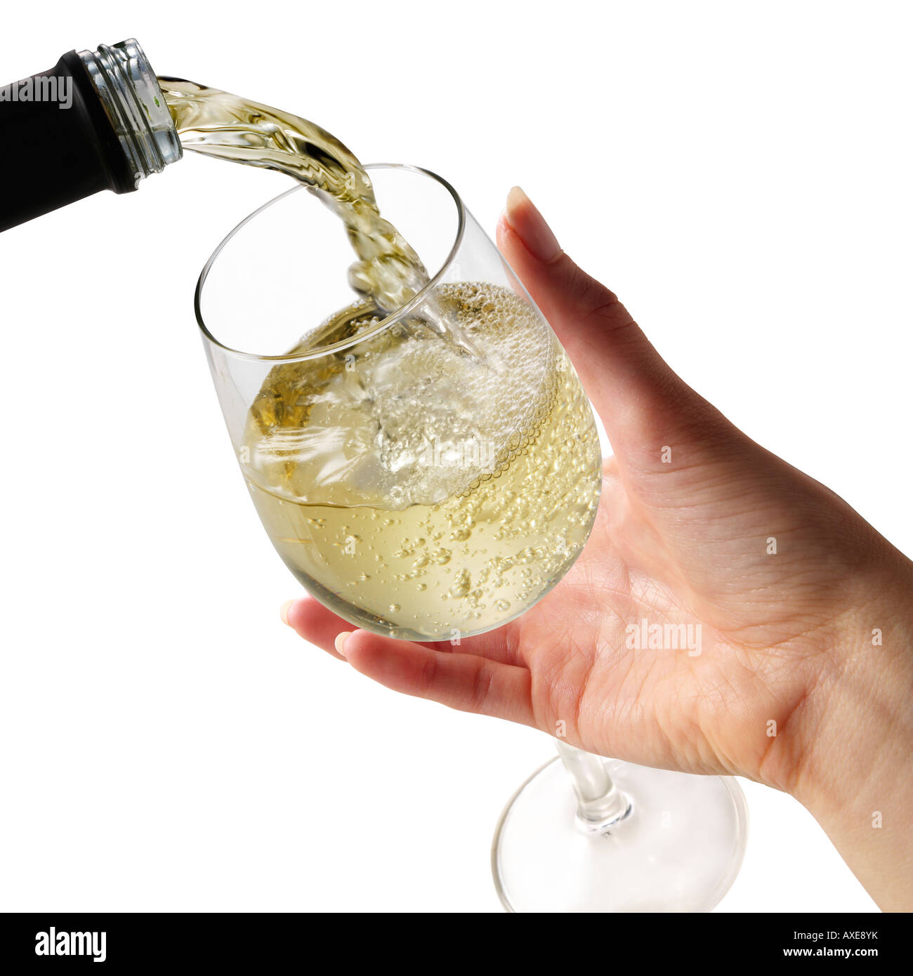 Il vino bianco che viene versato in un bicchiere da vino tenuto da una donna mano contro uno sfondo bianco Foto Stock