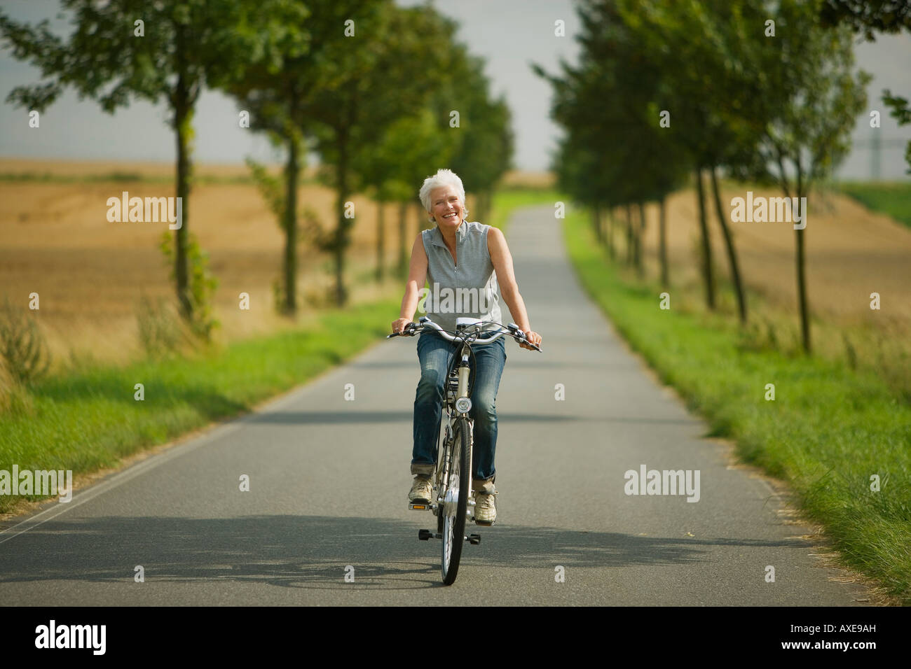 Senior donna ciclismo su strada Foto Stock