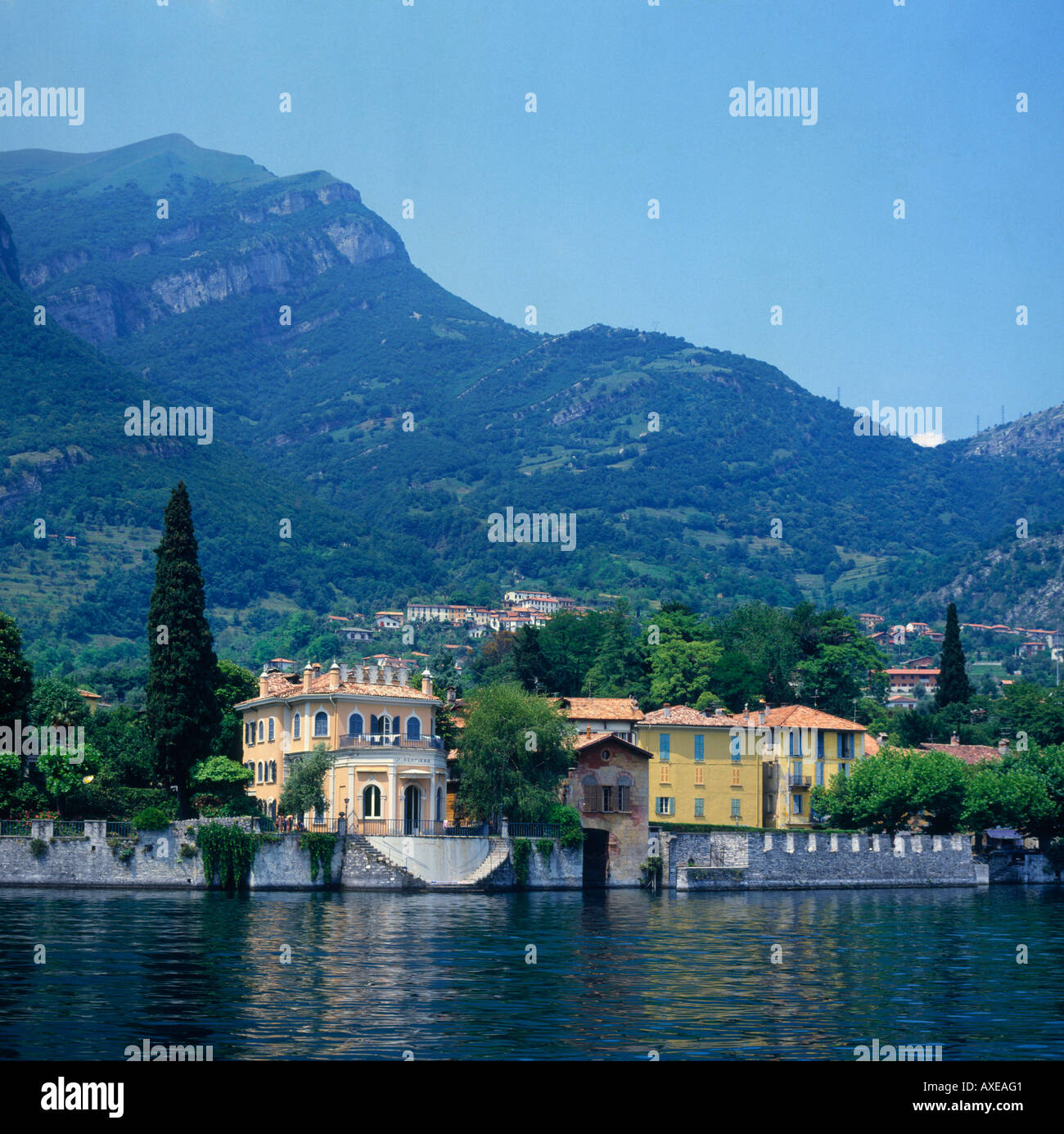 Incantevoli ville fronte mare con fronti di murata a bordo delle acque con le colline sopra a Tremezzo sul Lago di Como Lombardia Provincia Italia Foto Stock