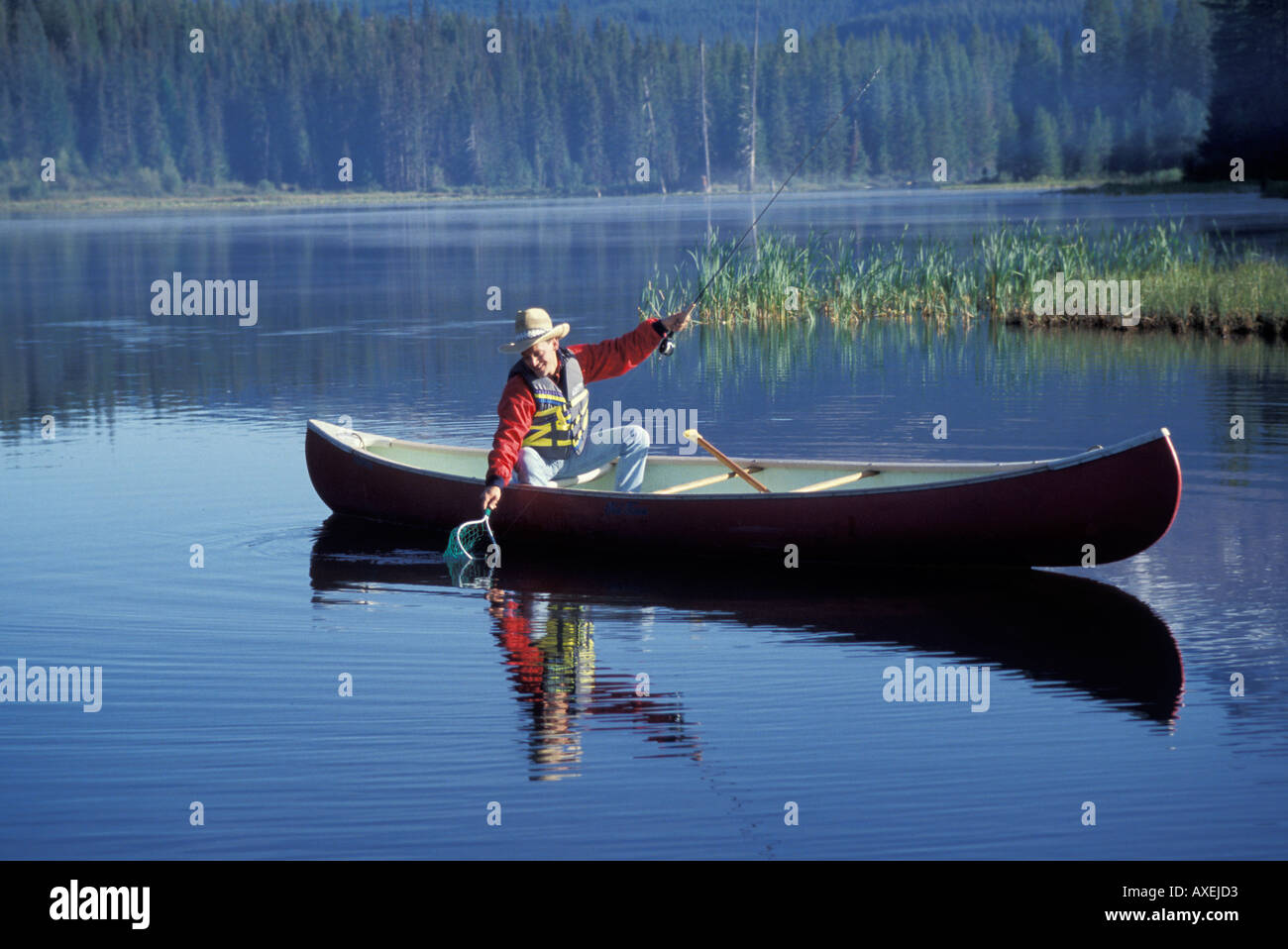 Cowboy caucasica la pesca da una canoa in un lago di montagna Foto Stock