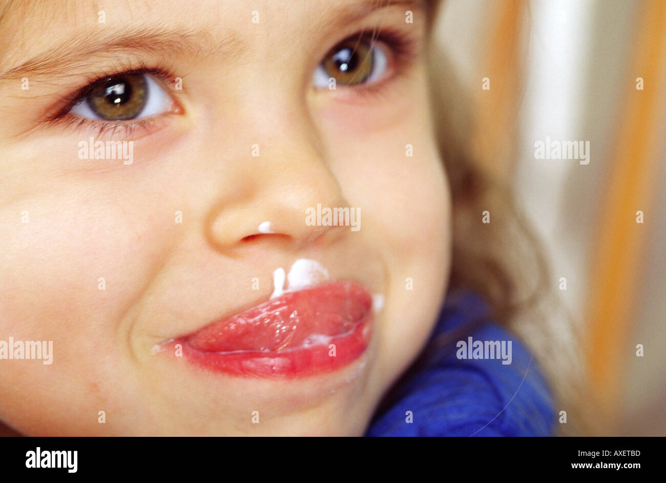 Ragazza femmina infanzia bambini bambino Età del cofano 0 5 mangiare felice leccare mettere stick la lingua di fuori lo yogurt di latte contenuto faccia vicino la piscina mi Foto Stock